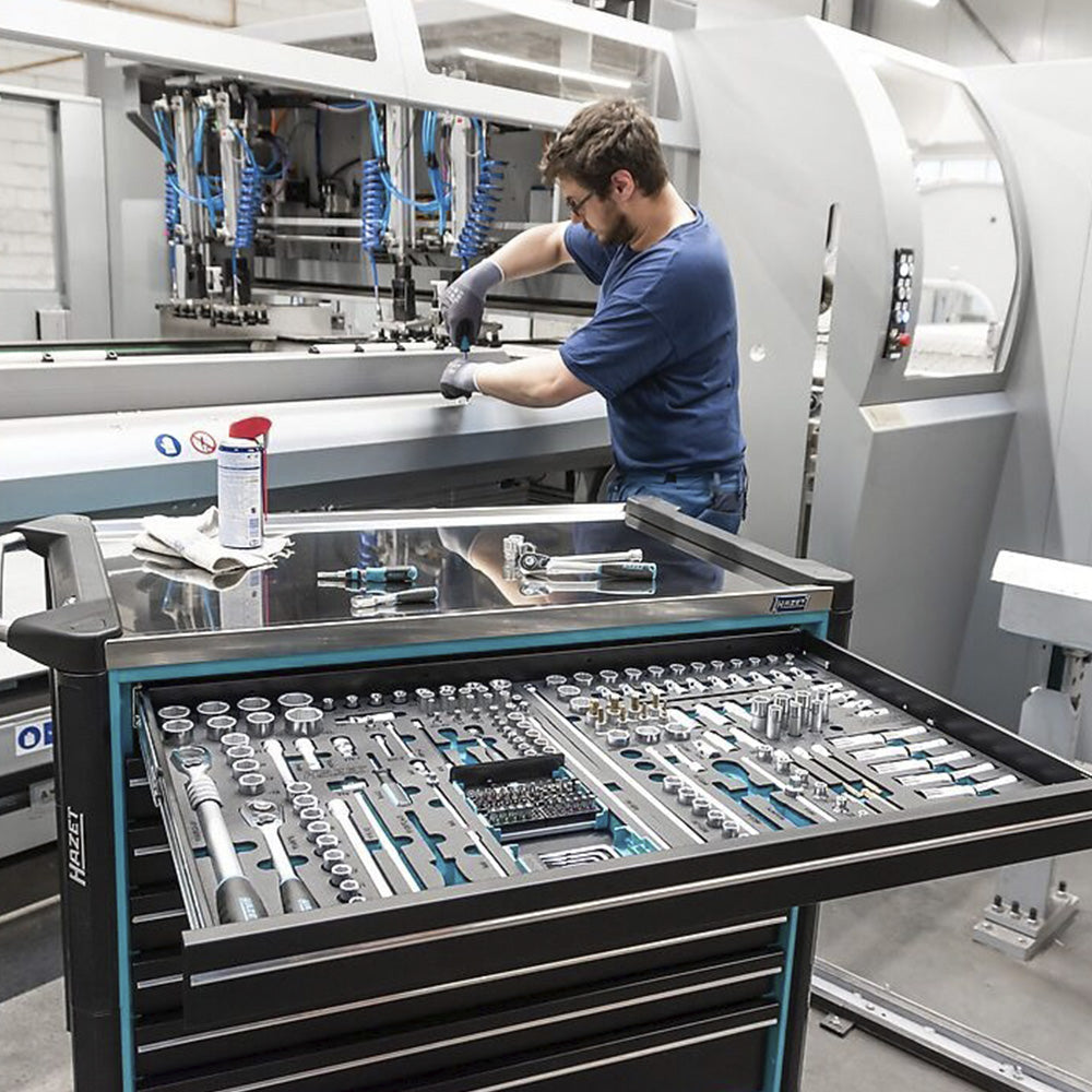 HAZET tool trolley with stainless steel worktop used by a mechanic during machine repair in a workshop.